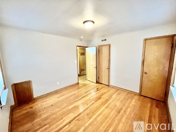 A room with wooden floors and three doors.
