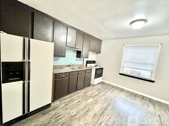 A kitchen with a white refrigerator and wooden floors.