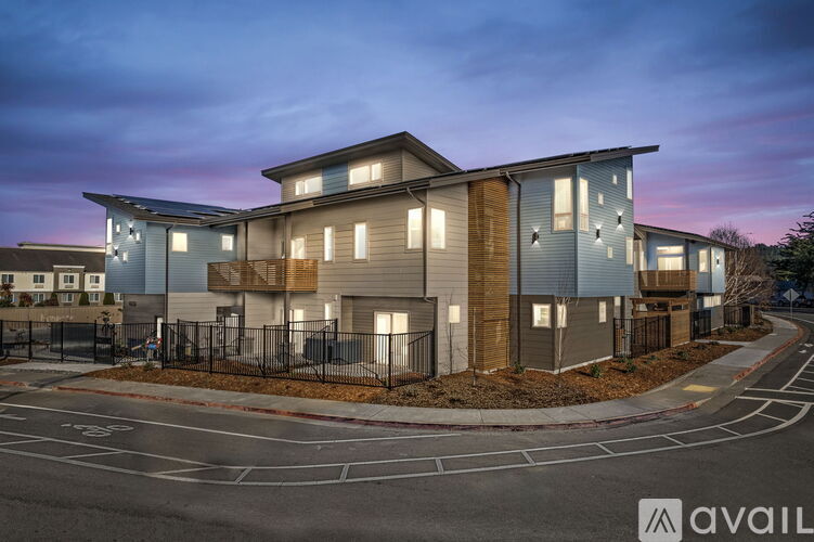 A modern residential building with a parking lot in front.