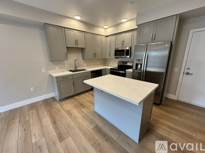 A kitchen with a white countertop and wooden flooring.