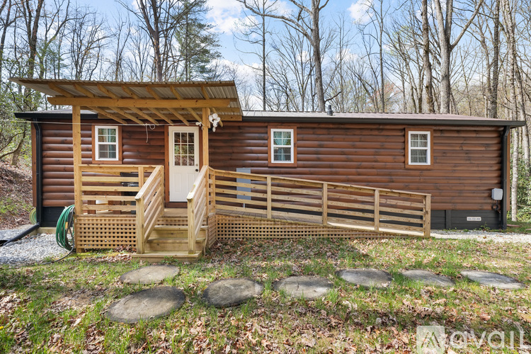 A wooden cabin with a porch and a green hose on the ground.