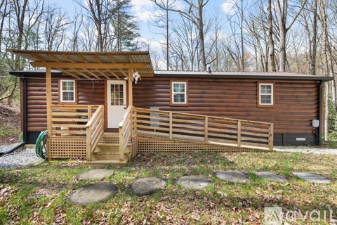 A wooden cabin with a porch and a green hose on the ground.