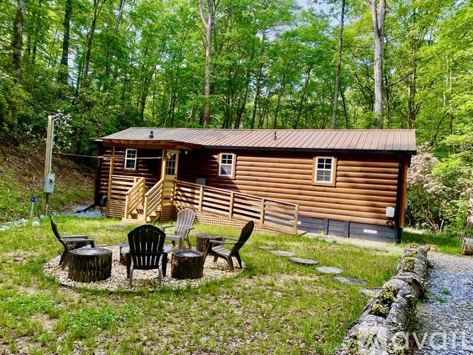 A wooden cabin is surrounded by trees and has a small porch.