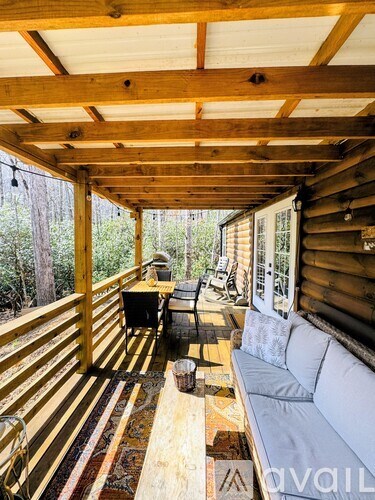 A wooden cabin is surrounded by trees and has a small porch.