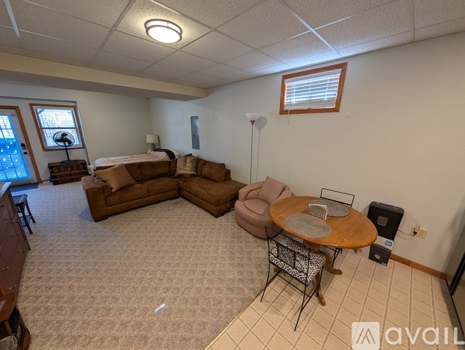 A living room with a brown sofa set and a round wooden table.