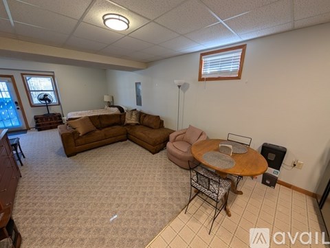 A living room with a brown sofa set and a round wooden table.