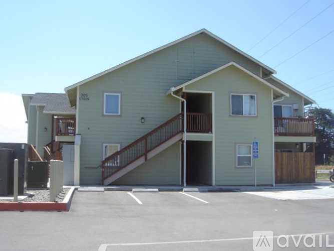 A two-story building with a garage and a balcony on the second floor.