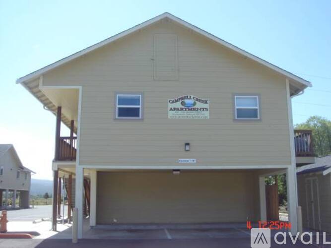 A two-story building with a garage and a sign that says "Campbell Apartments".