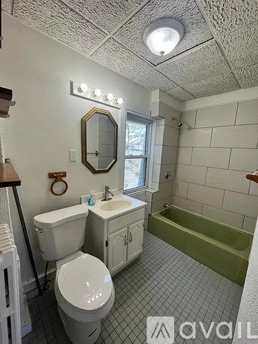 A bathroom with a toilet, sink, mirror, and tub.