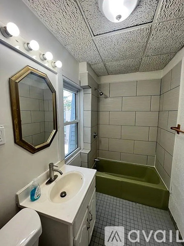 A bathroom with a white sink, toilet, and a mirror with lights above it.