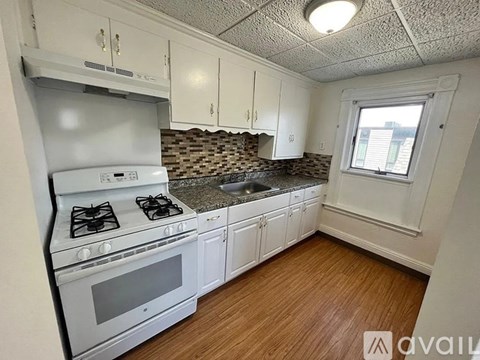 A kitchen with a white stove and cabinets.