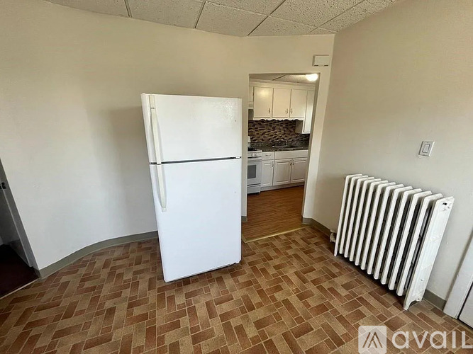 A white fridge in a room with a brown floor.
