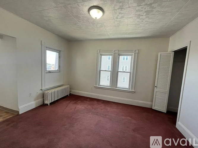 A room with a red carpet and a window with a view of a building.