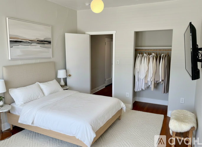 A bedroom with a large bed and a television mounted on the wall.