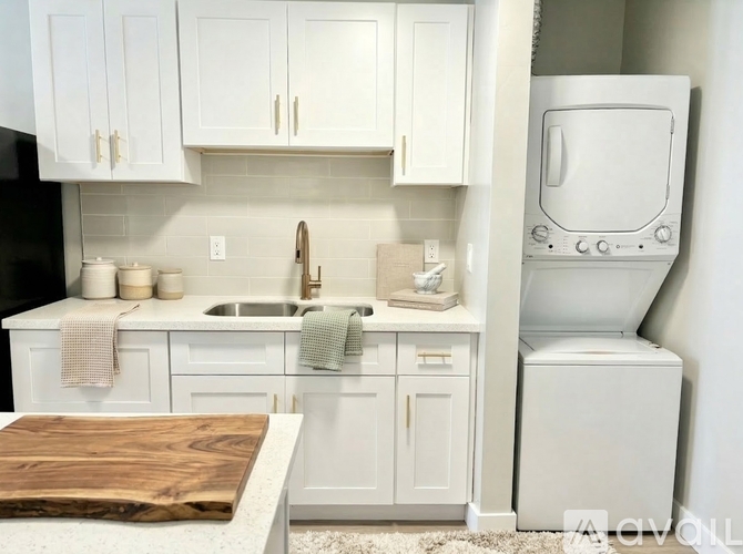 A kitchen with white cabinets and a wooden cutting board on the counter.
