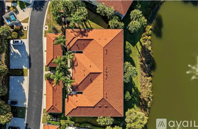 A bird's eye view of a house with a red roof and a swimming pool in the backyard.