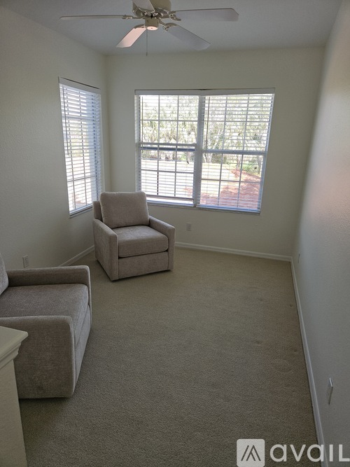 A living room with a beige carpet and two grey chairs.
