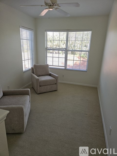 A living room with a beige carpet and two grey chairs.