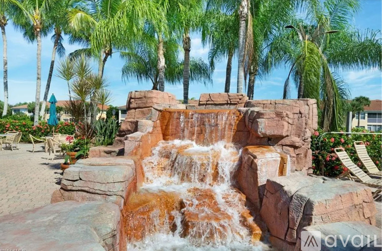 A waterfall in a garden surrounded by palm trees.