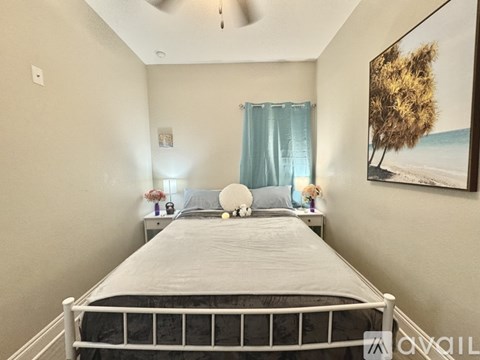 A bedroom with a large bed and a painting on the wall.