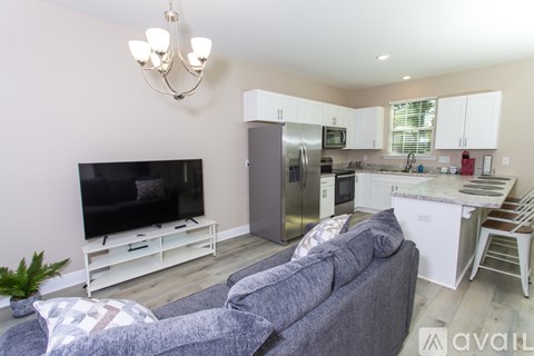 A living room with a grey couch and a television on a white stand.