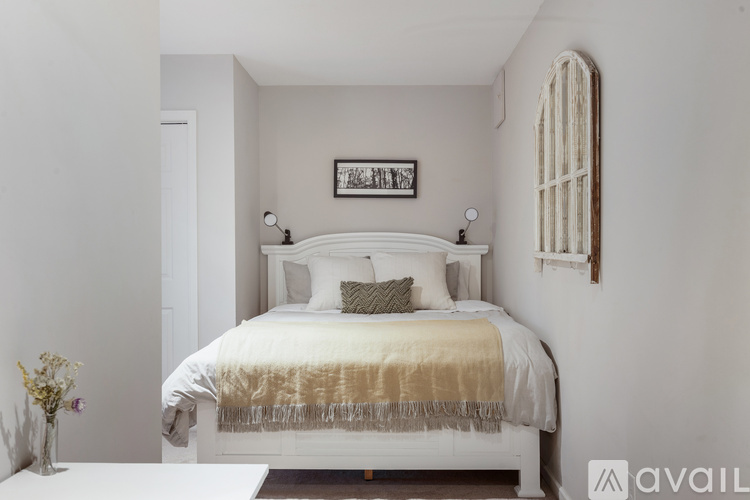 A bedroom with a white bed and a framed picture on the wall.