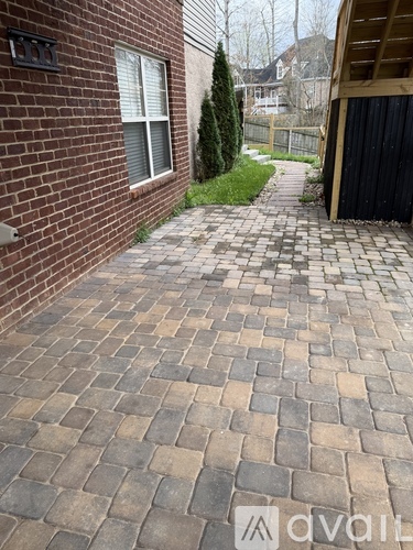 A brick walkway leads to a black door.