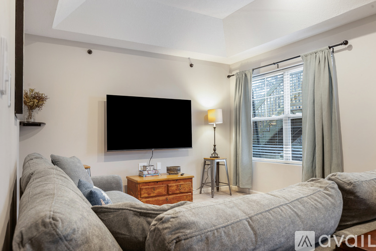 A living room with a grey sofa and a flat screen TV mounted on the wall.