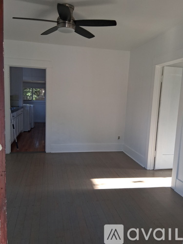 A room with a ceiling fan and wooden flooring.