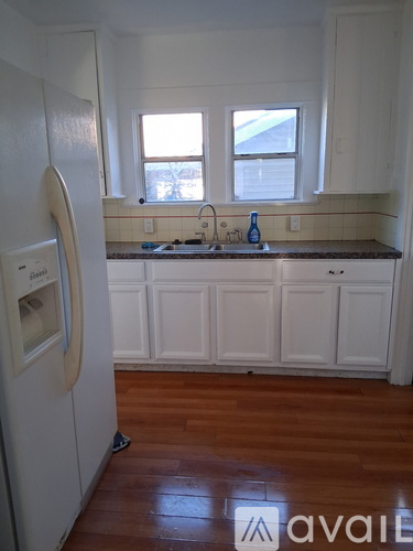 A kitchen with white cabinets and a wooden floor.
