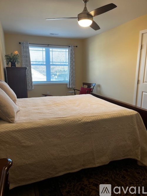 A bedroom with a bed, a ceiling fan, and a window.