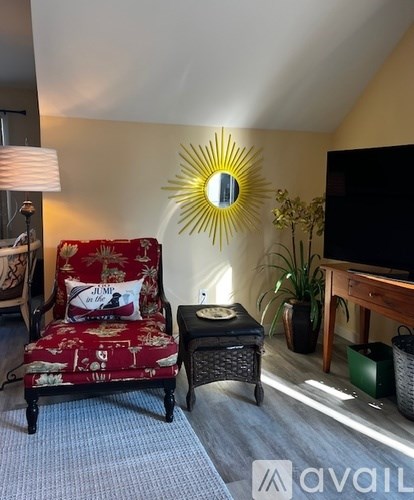 A living room with a red chair and a yellow sunburst mirror.