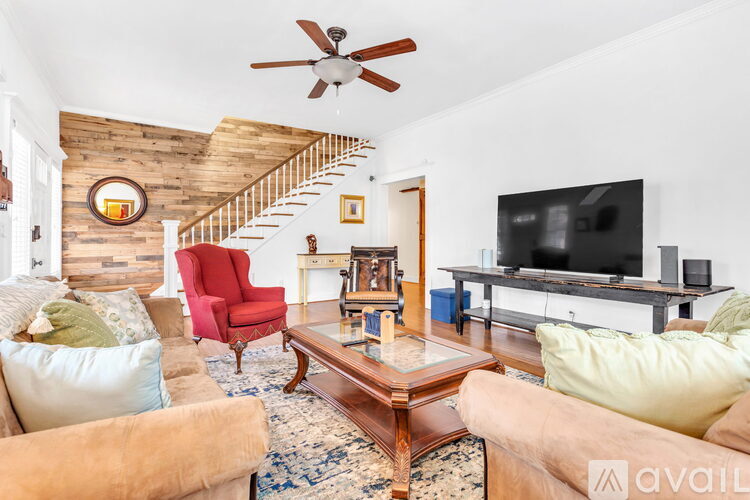 A living room with a red chair and a wooden staircase.
