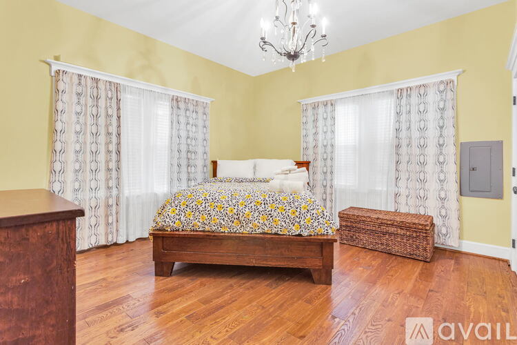 A bedroom with a bed, nightstand, and a chandelier.