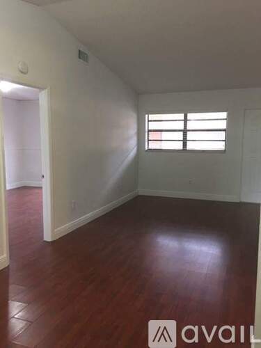 A room with wooden floors and a window with blinds.