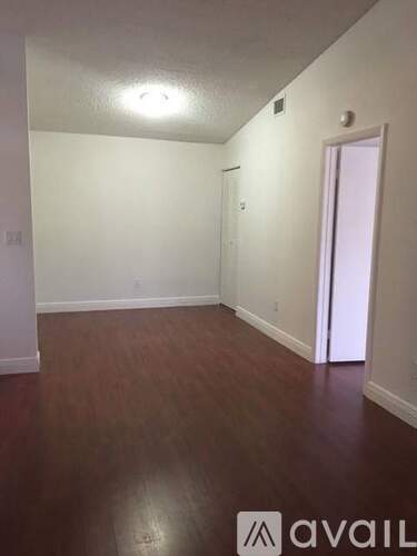A room with wooden flooring and white walls.