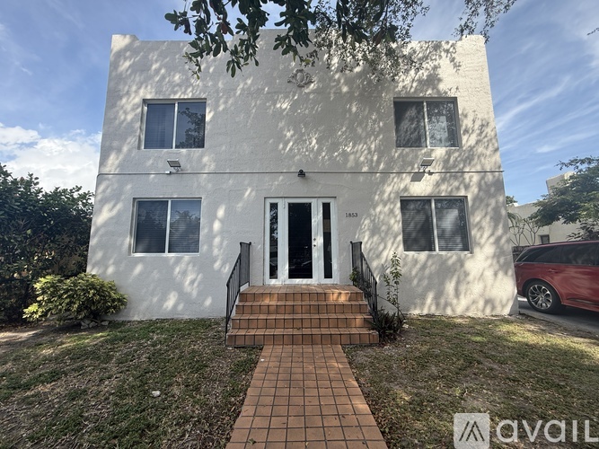 A white two-story house with a brick walkway leading to the front door.