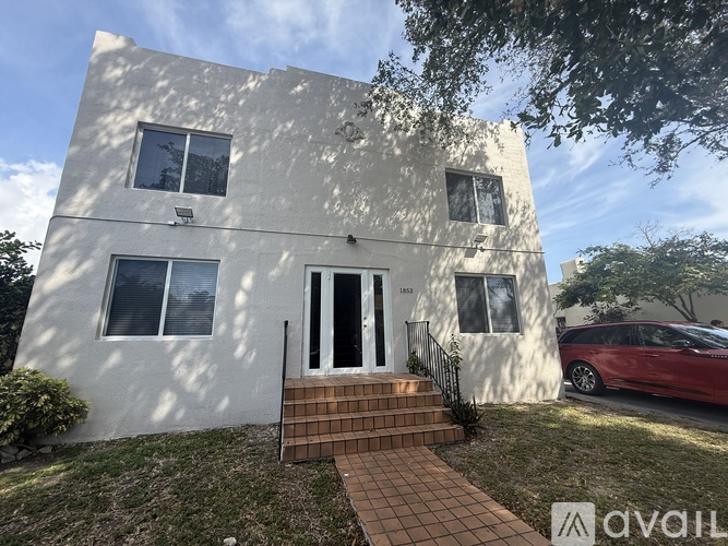 A white two-story house with a red car parked in front.