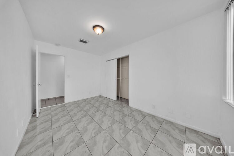 A spacious room with a tiled floor and a single light fixture on the ceiling.