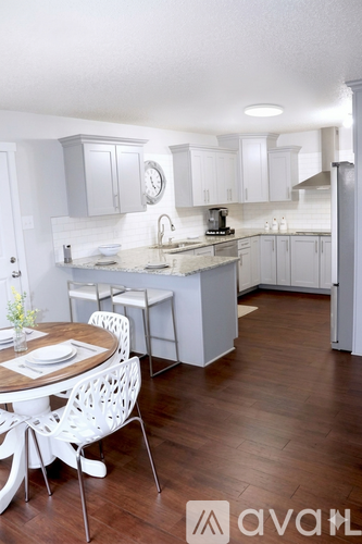 A kitchen with white cabinets and a wooden floor.
