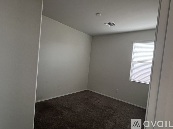 A room with a carpeted floor and a window with blinds.