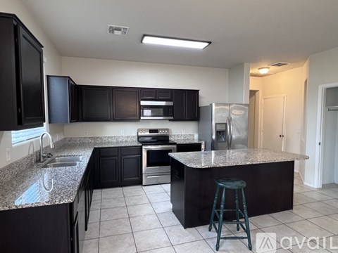 A kitchen with black cabinets and granite countertops.