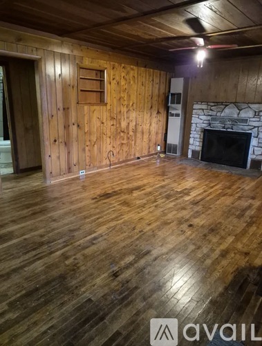 A room with wooden floors and a stone fireplace.