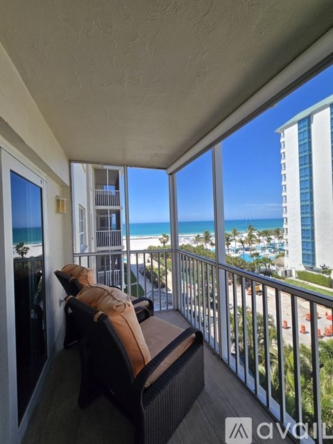 A balcony with a view of the beach and a building in the distance.