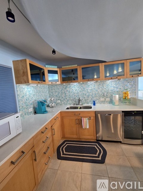 A kitchen with wooden cabinets and a blue kettle on the counter.