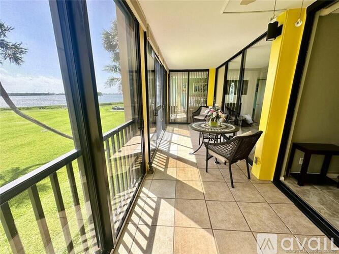 A balcony with a table and chairs overlooking a grassy area.