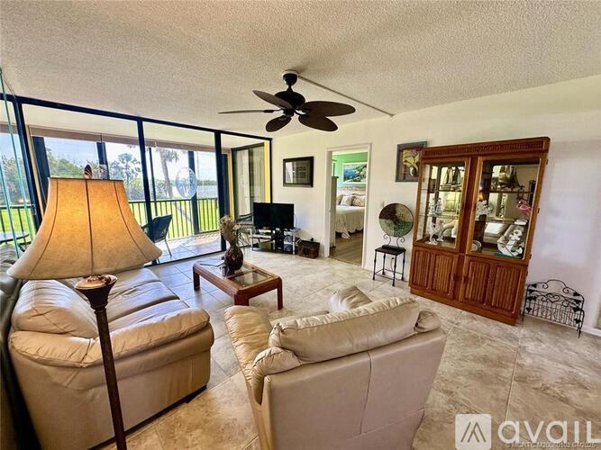 A living room with a lamp, a couch, a chair, a coffee table, a television, and a ceiling fan.
