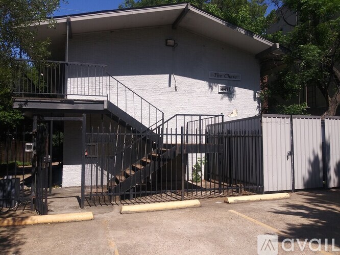 A white building with a black gate and a sign that says "The Chase".