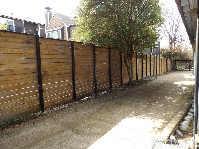 A long wooden fence runs along a sidewalk.