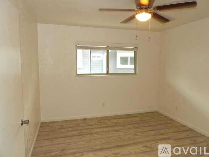 A room with a ceiling fan and wooden flooring.